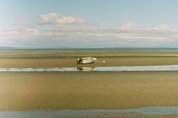 desolate boat sitting on a sandbar in the sun