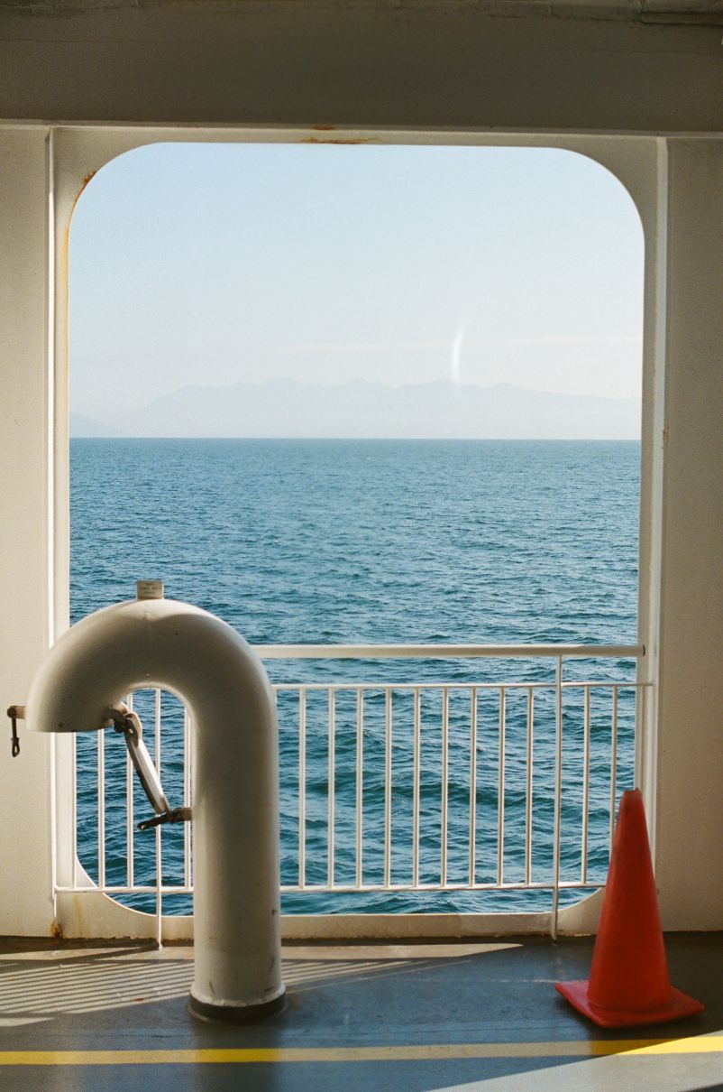 image of the wide open sunbathed ocean through the porthole on lower deck